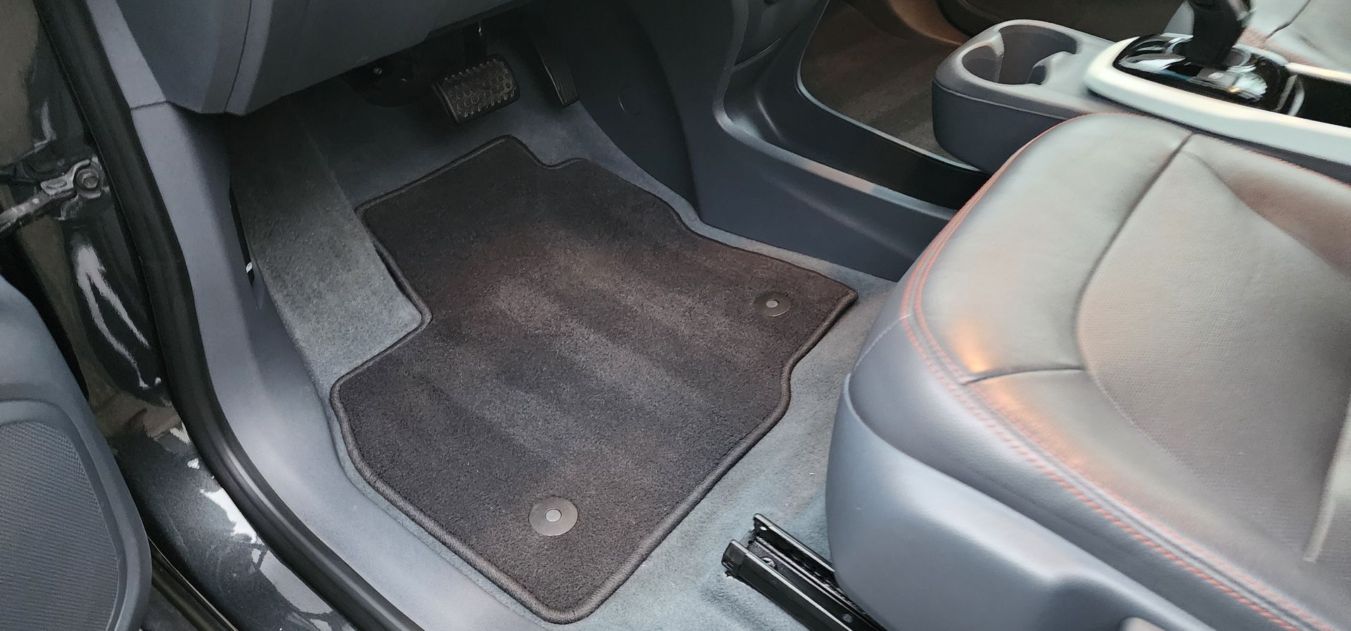 Car interior with gray front seats and dark floor mats in the passenger footwell