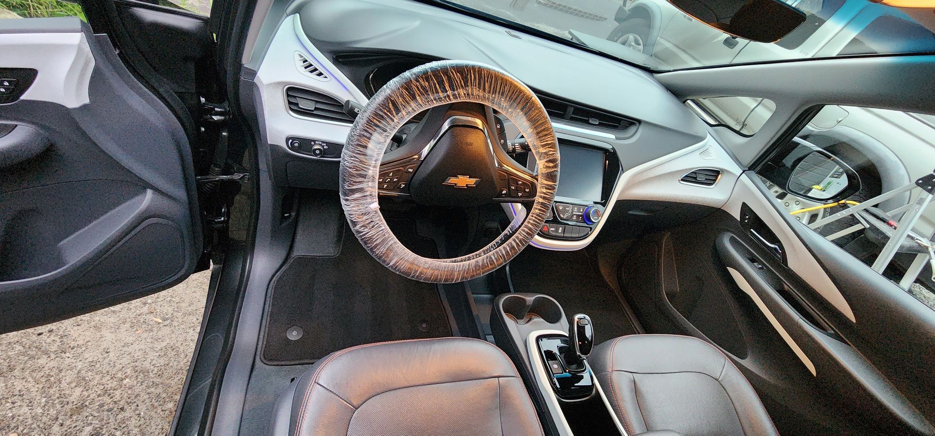 Luxury car interior with tan leather seats, wood steering wheel, and white dashboard trim