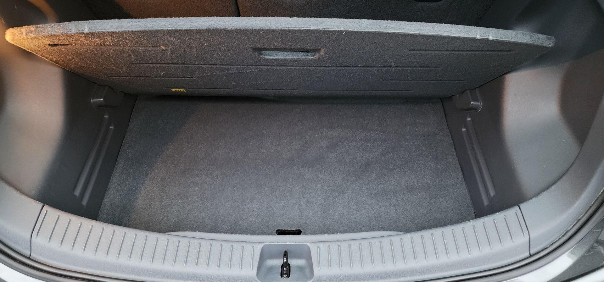 Empty car trunk with gray carpeted cargo floor and open hatch