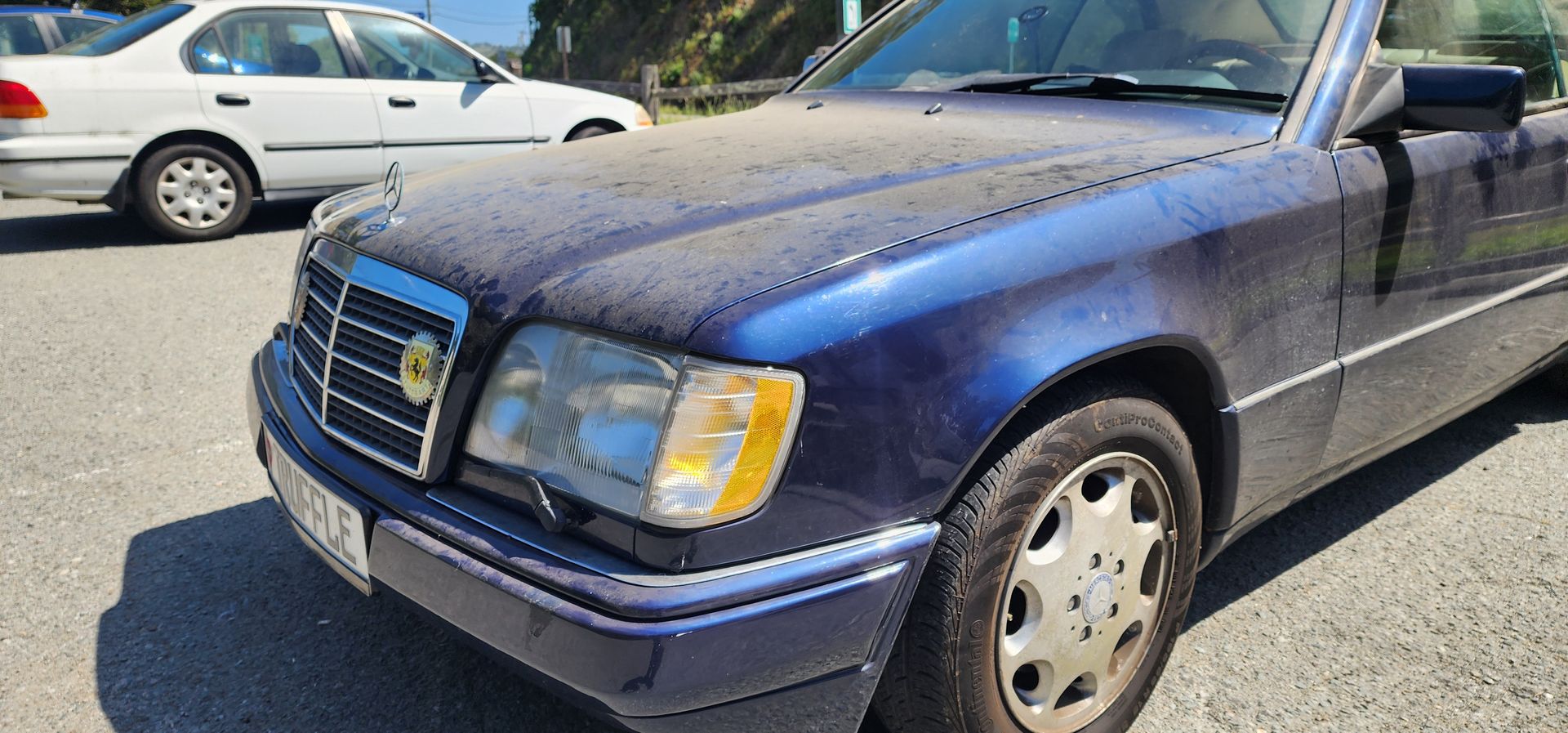 Dark blue sedan parked outdoors beside a white car