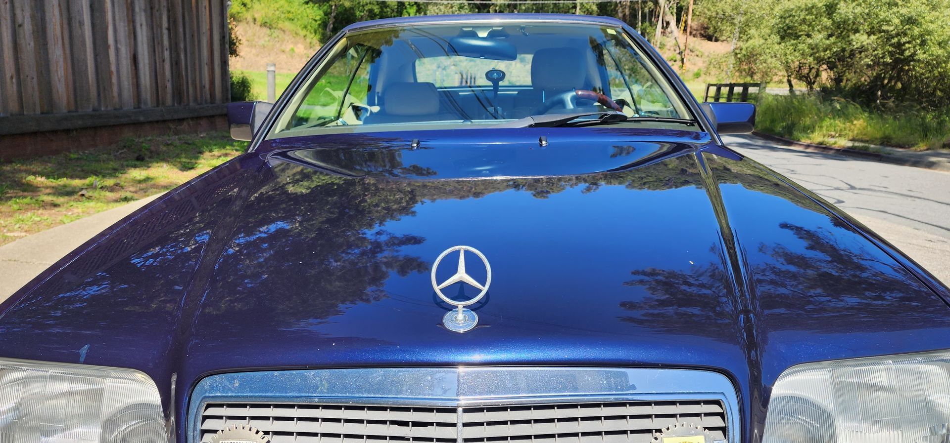 Front view of a blue Mercedes-Benz parked outdoors in sunlight