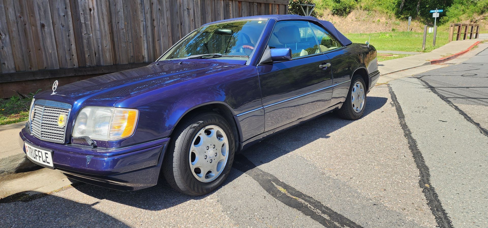 Purple sedan parked on a sunny roadside near a grassy embankment