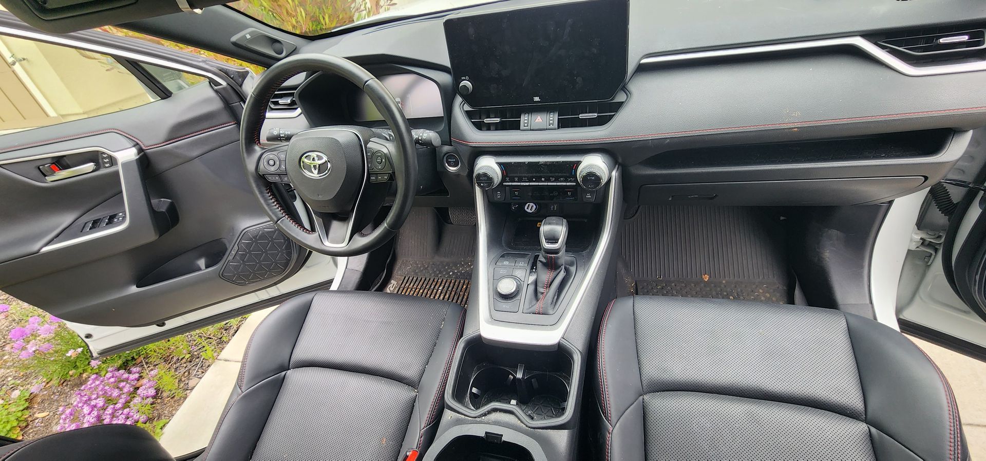 Car interior with black seats, steering wheel, center console, and dashboard screen.