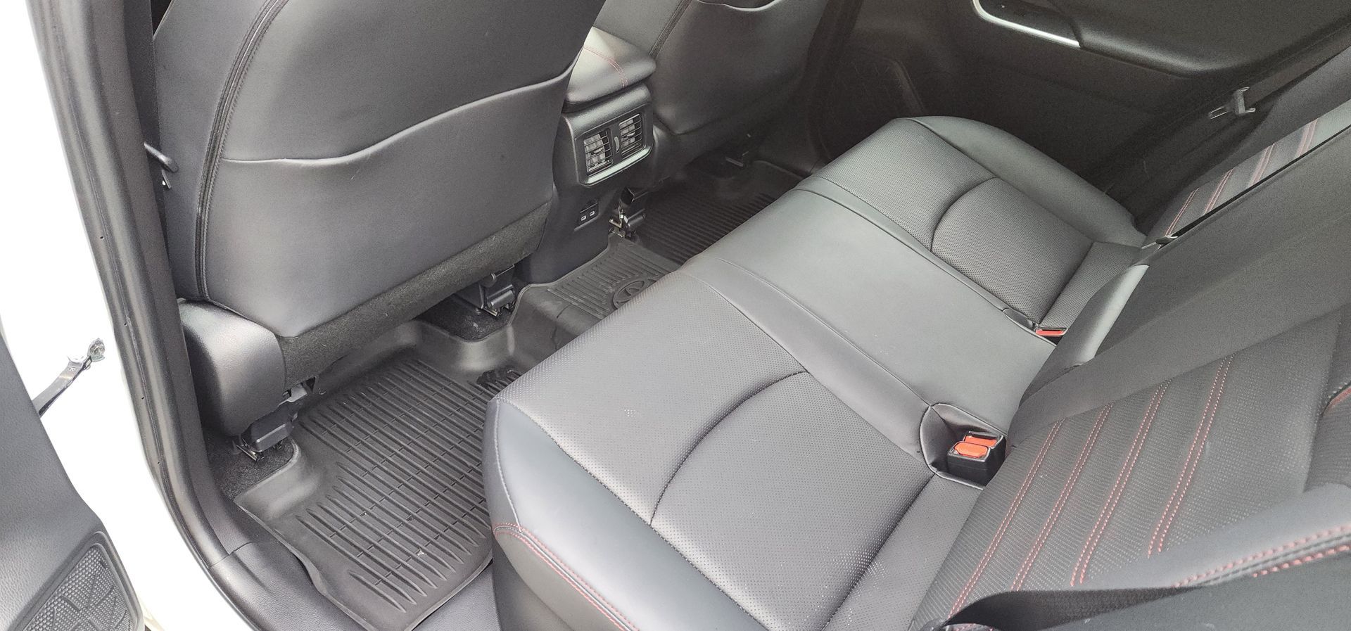 Rear car seats in black and gray upholstery with a floor mat in view