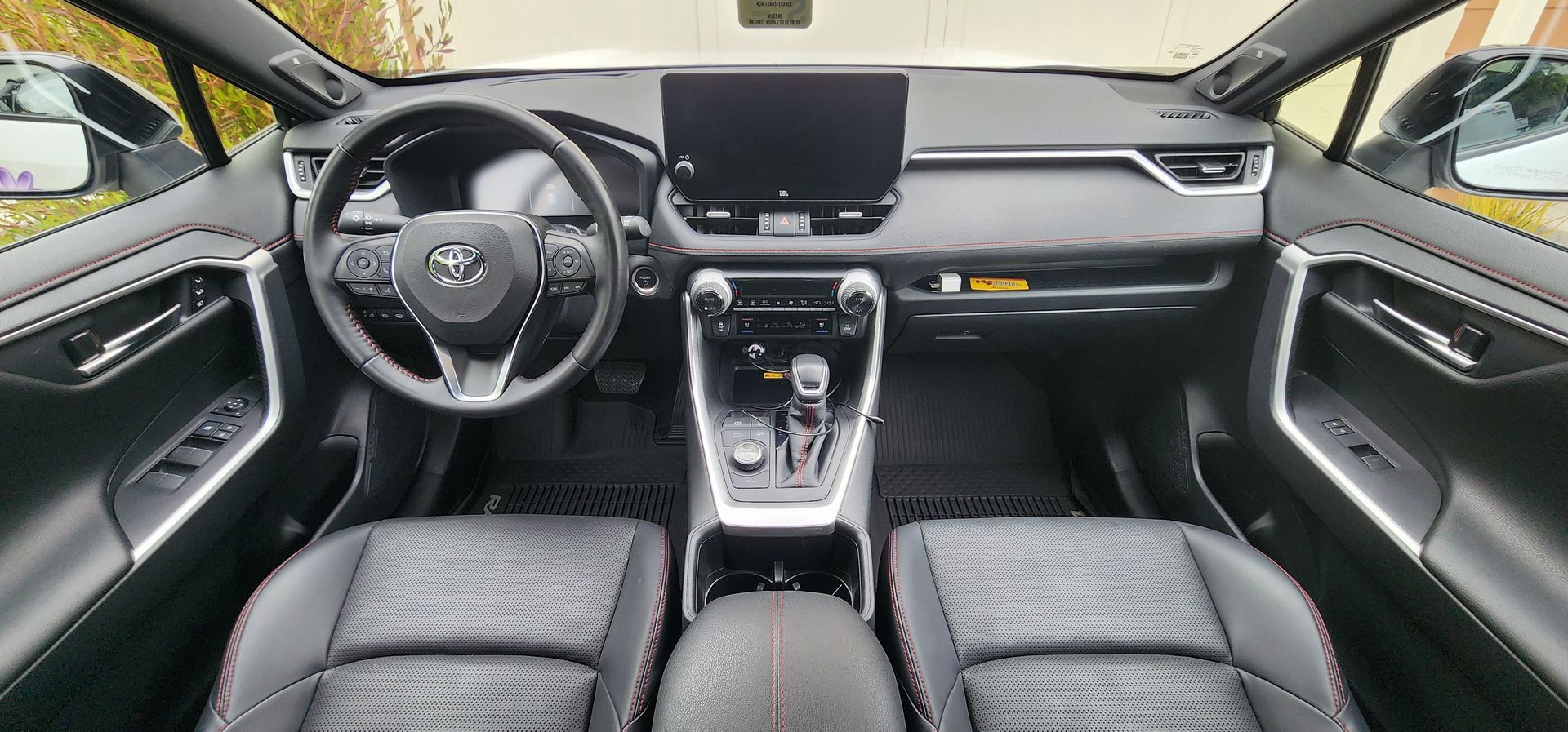 Car interior view with black seats, steering wheel, dashboard, and center console.
