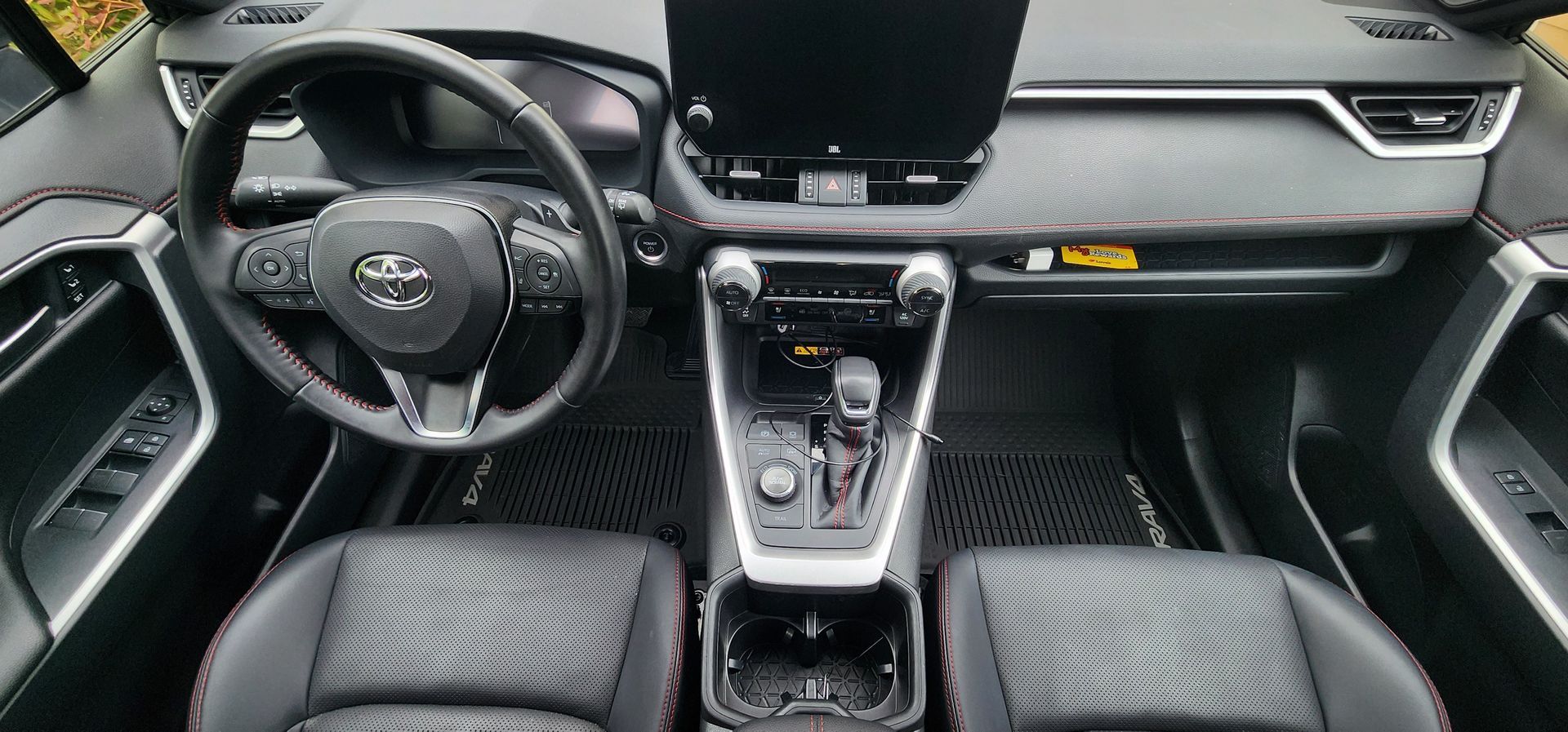 Interior of a Toyota car, showing the steering wheel, dashboard, center console, and front seats.