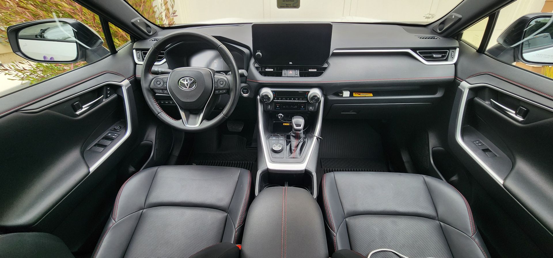 Car interior view with black leather seats, steering wheel, dashboard, and center console