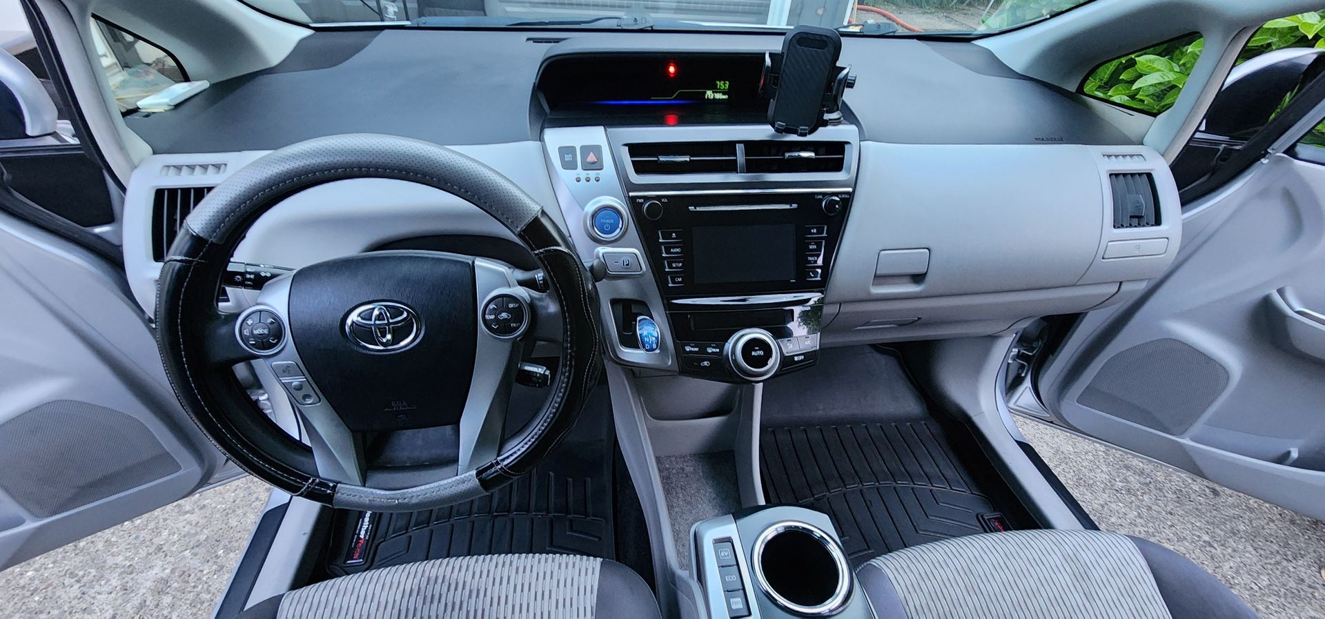 Car dashboard and steering wheel view from front seats, with center console and gray upholstery, empty interior.