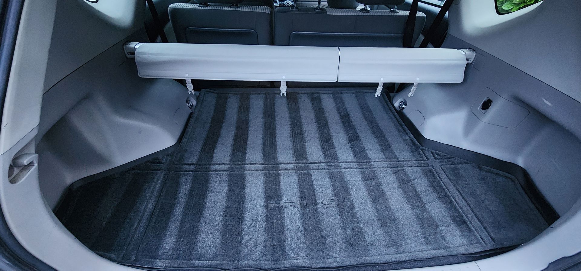 Empty car trunk with a black rubber cargo mat and gray interior trim