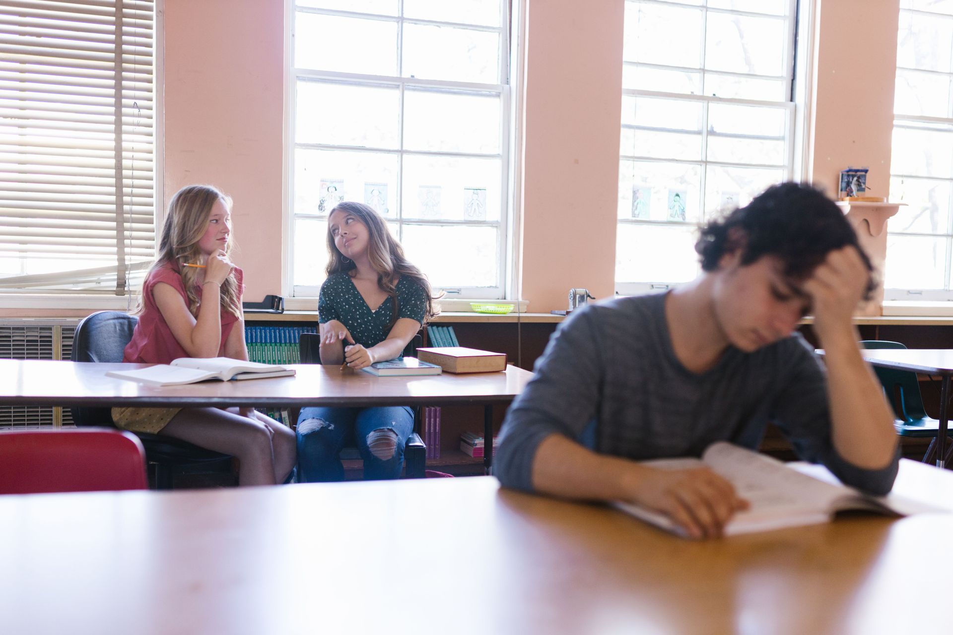Students sitting in a classroom, with one in the foreground holding their head over a notebook.