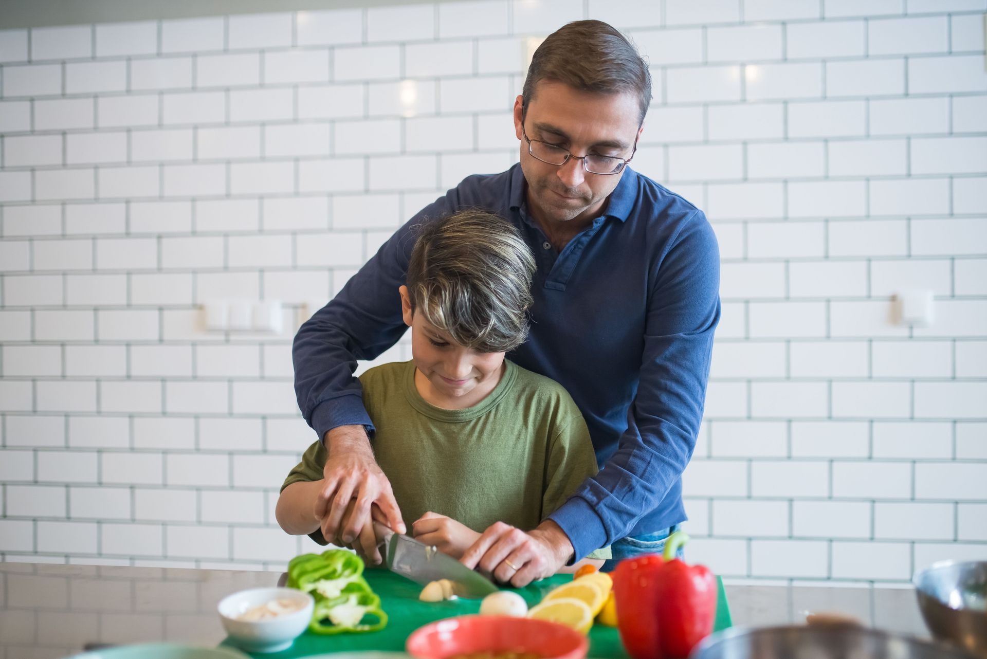 Two people preparing vegetables together in a kitchen, one guiding the other while chopping.