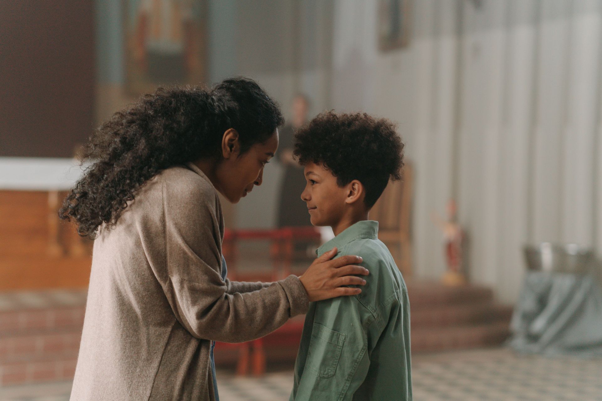 Two people standing close, one comforting the other in a softly lit indoor setting