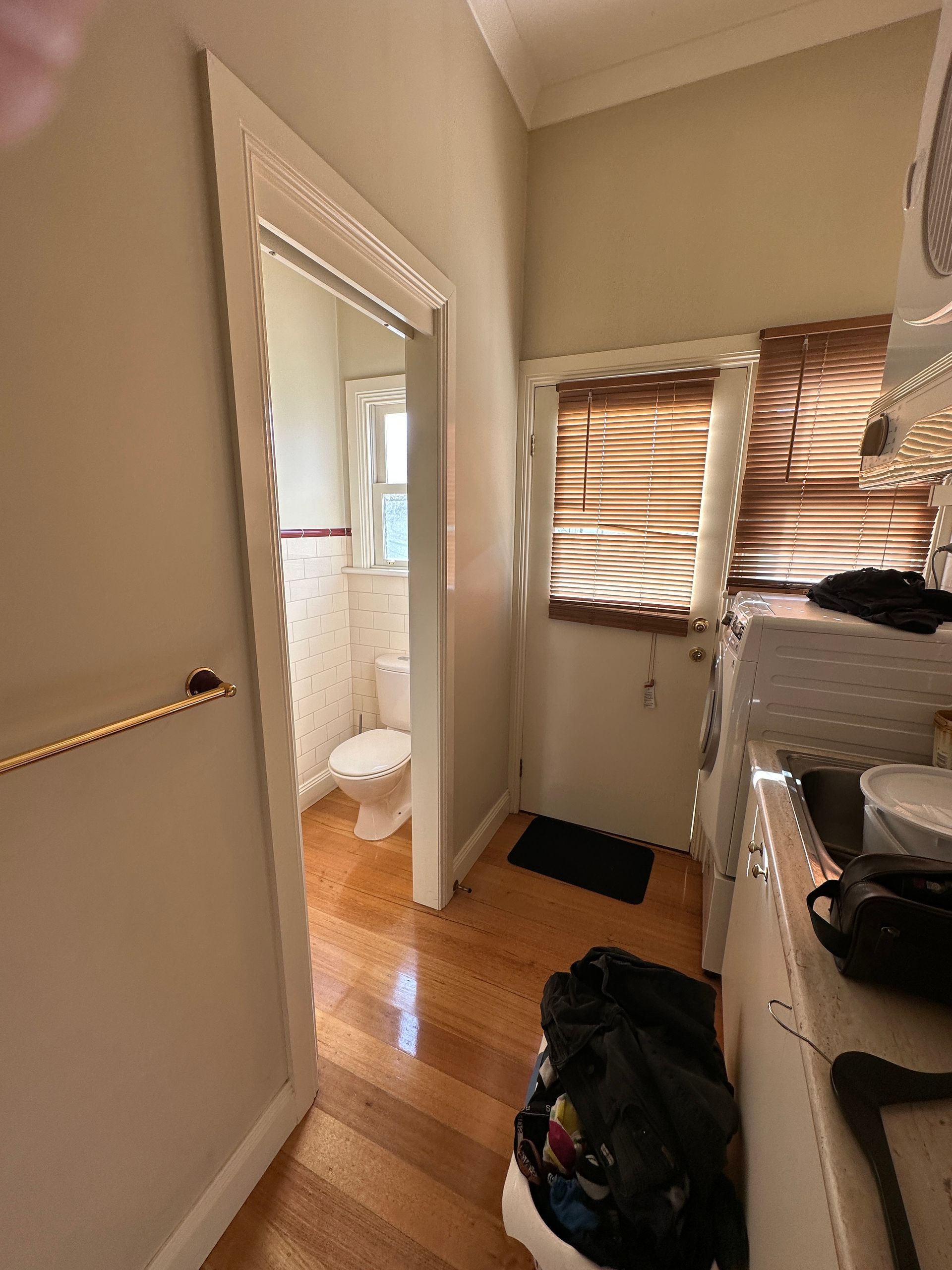 A view to the service yard door  between the dated laundry with minimal cabinetry and old powder room in a Shepparton home before  the installation of modern cabinetry as part of a broader home renovation.