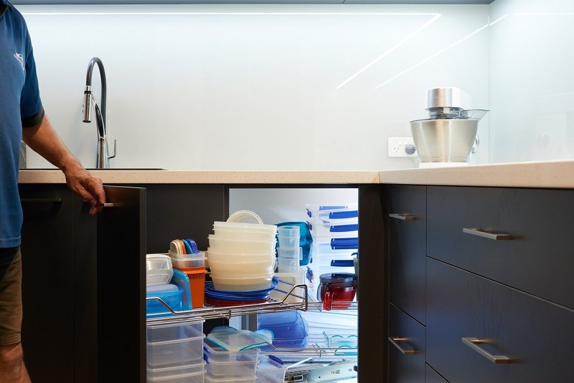 Homeowner pulling out corner cupboard to reveal Magic Corner carousel with easy accessed kitchenware