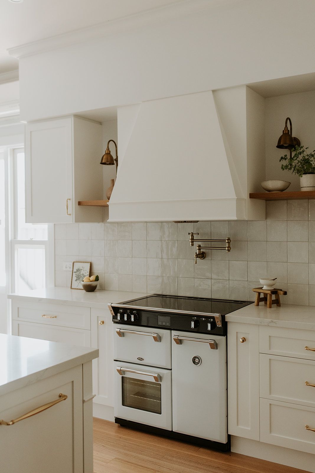 Bright white kitchen with vintage stove, tiled backsplash, and open shelves with decor