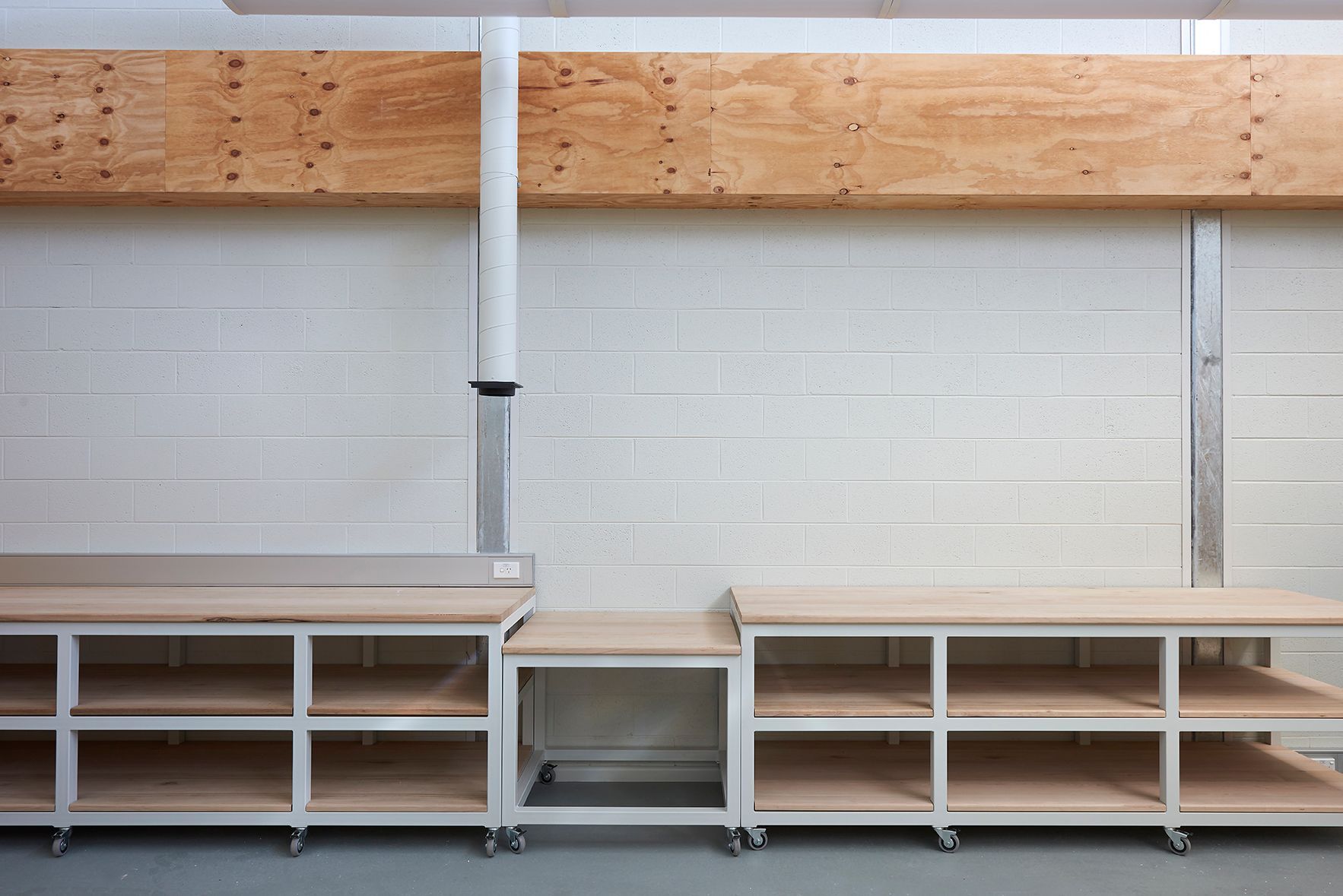 Empty workshop wall with wooden shelves and white brick background