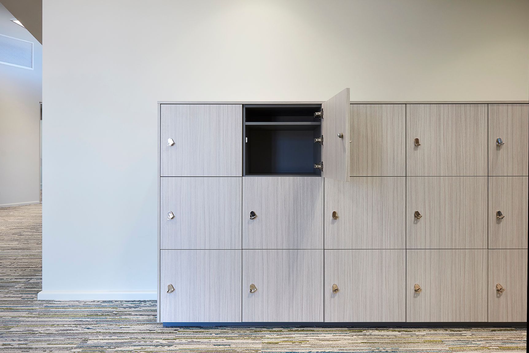Wooden locker cabinets in a hallway, one open to an empty black shelf.