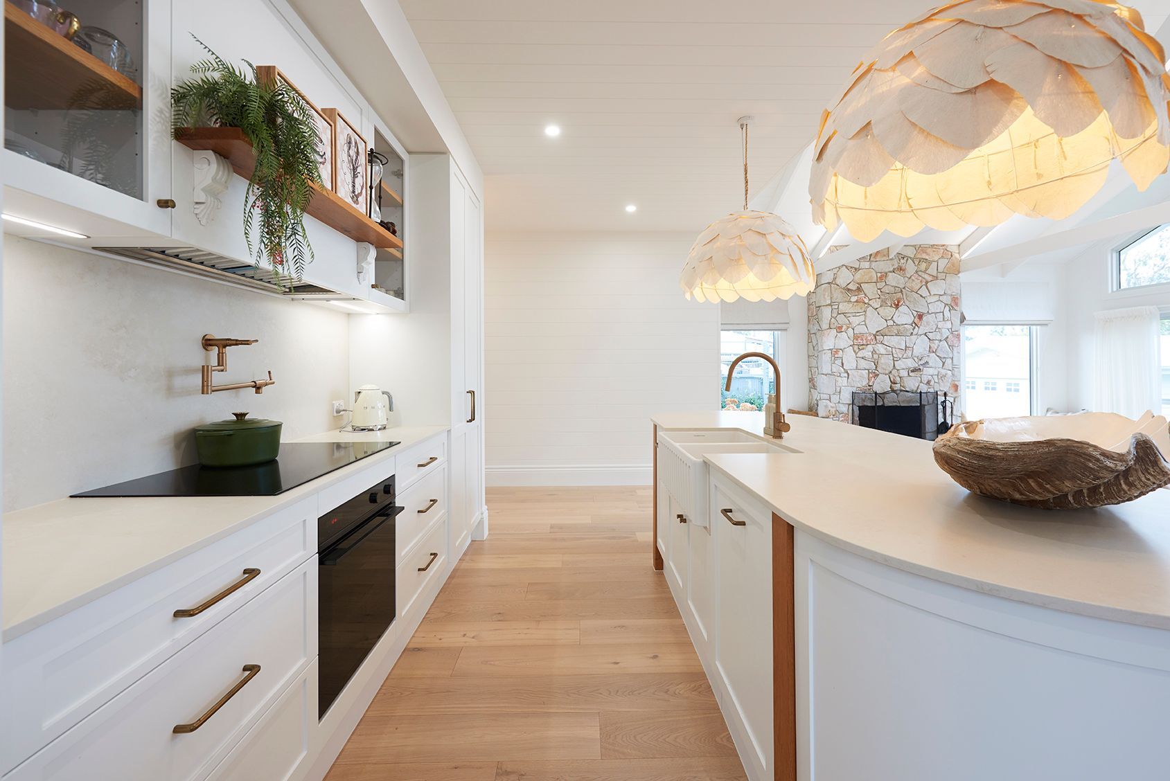 Bright modern kitchen with white cabinets, wood floors, and island under pendant lights