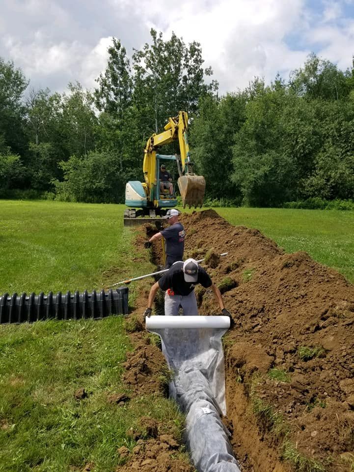 Two men are working on a septic system in a field.