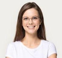 Smiling person with glasses and long brown hair wearing a white shirt against a light background