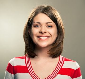 Smiling woman in a red-and-white striped shirt against a neutral background