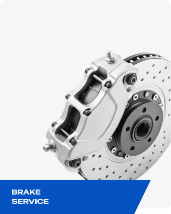 Silver brake caliper and perforated disc rotor with “BRAKE SERVICE” label on blue banner | Elite Automotive & Diesel Repair