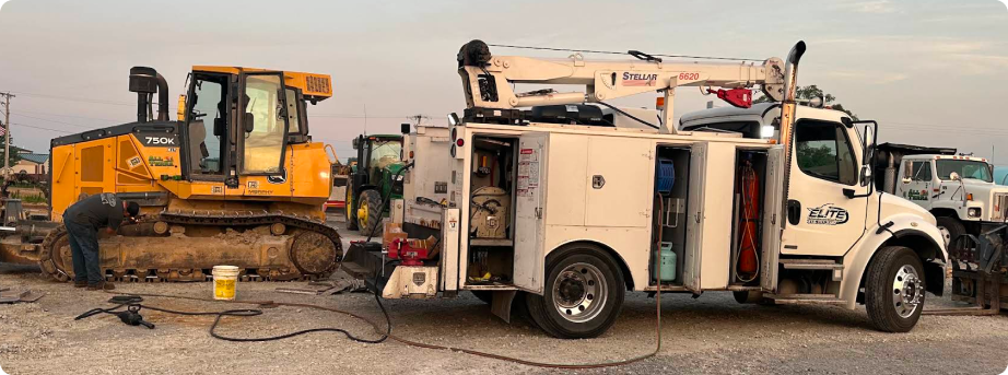 Construction site with yellow excavator and white utility truck on a dirt lot | Elite Automotive & Diesel Repair