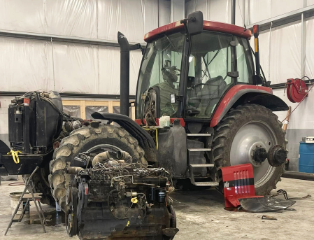 Red tractor in a workshop, with engine parts removed and tools on the floor | Elite Automotive & Diesel Repair