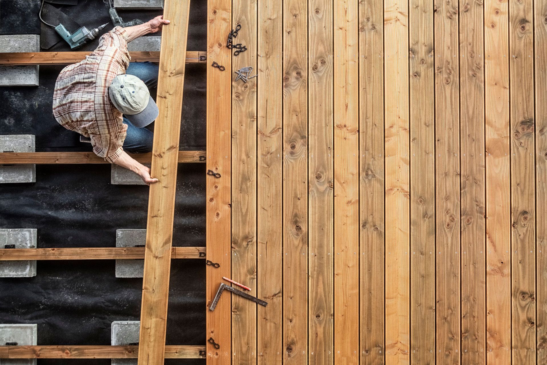 A man is climbing a ladder to install a wooden deck.