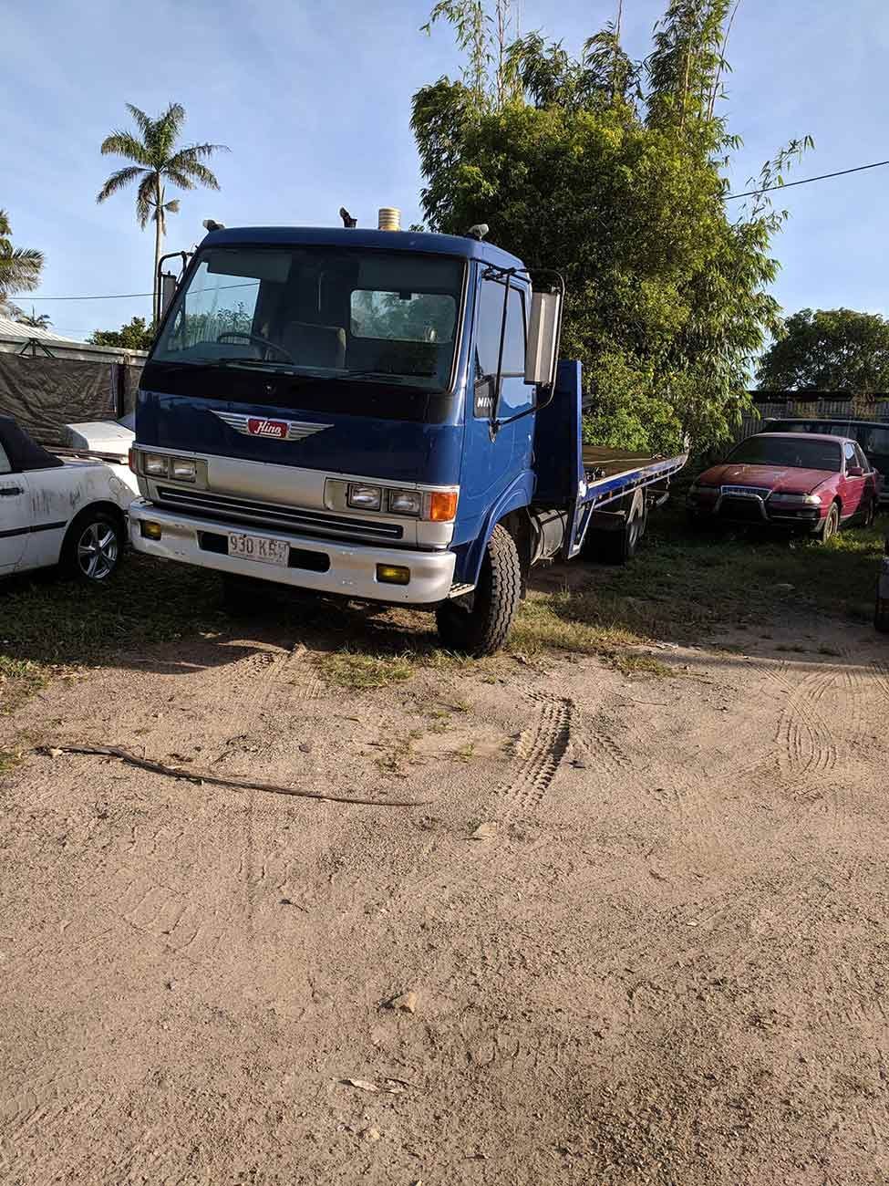 A Blue Truck Is Parked in A Dirt Lot Next to A White Car — Bakers Creek Wreckers In Emu Park, QLD