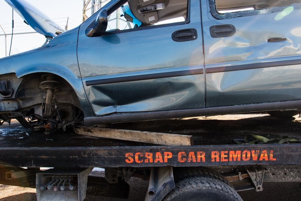 A Scrap Car Is Sitting On Top Of A Tow Truck — Bakers Creek Wreckers In Gracemere, QLD