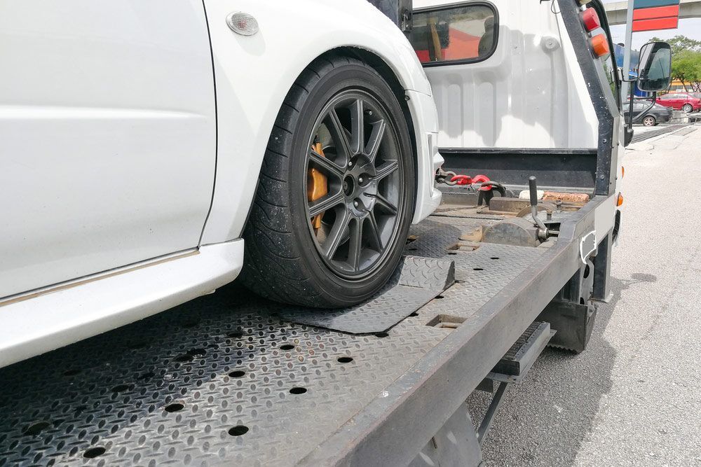 A White Car Is Being Towed by A Tow Truck — Bakers Creek Wreckers In Yeppoon, QLD