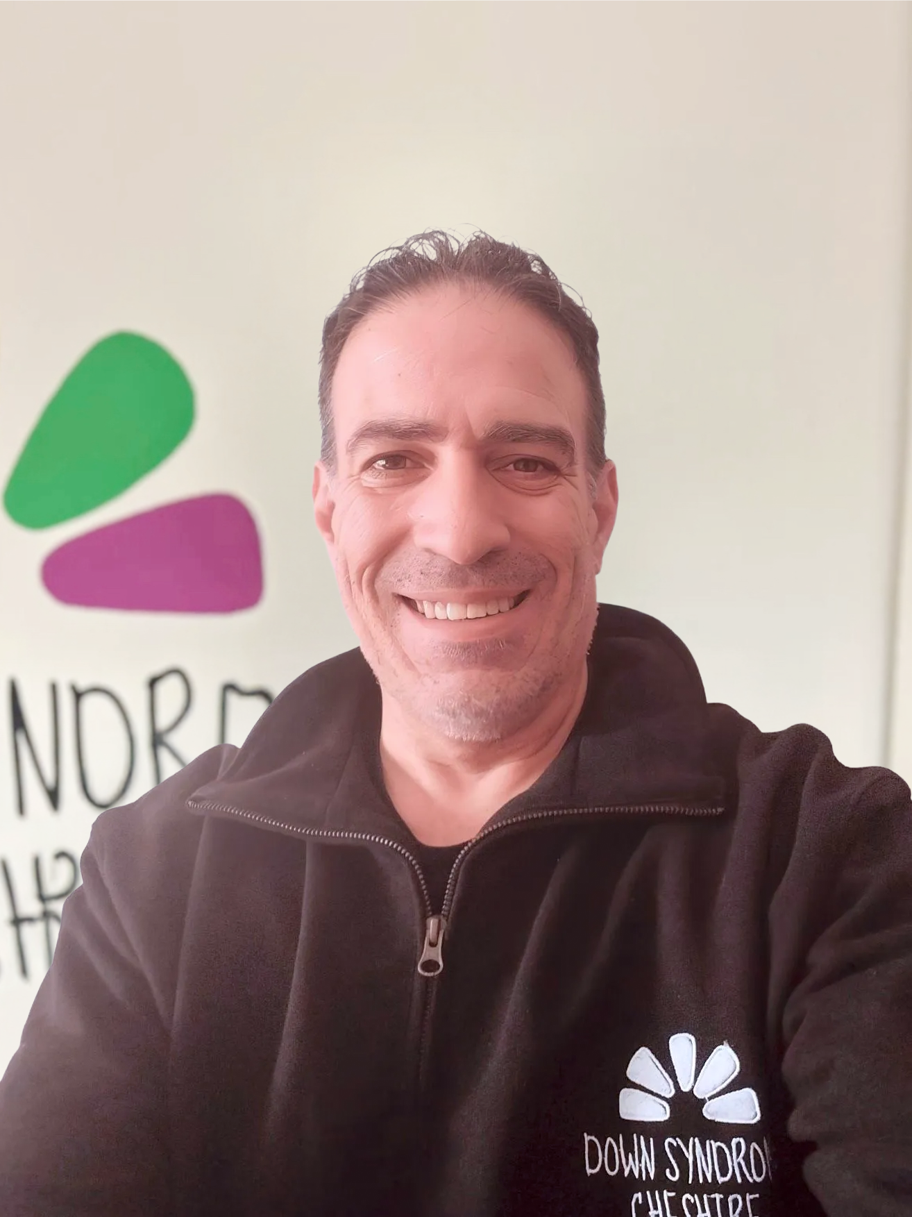a man wearing a black hoodie is smiling for the camera