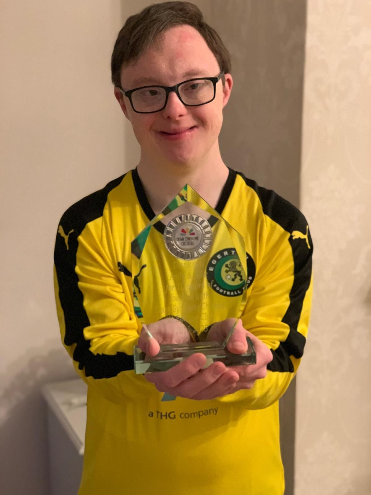 a young boy wearing glasses is holding a soccer ball .