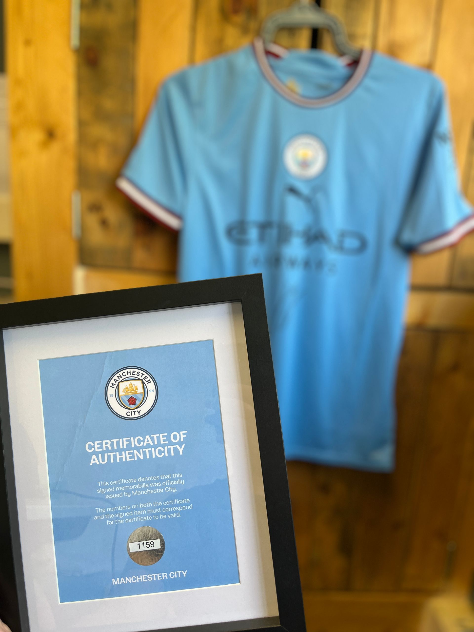 A framed certificate of authenticity next to a blue shirt