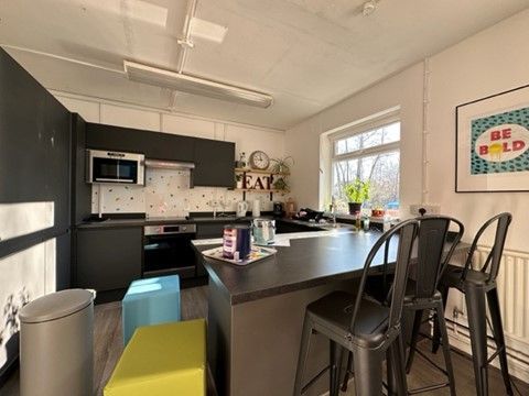 a kitchen with a large island , stools , and a microwave .