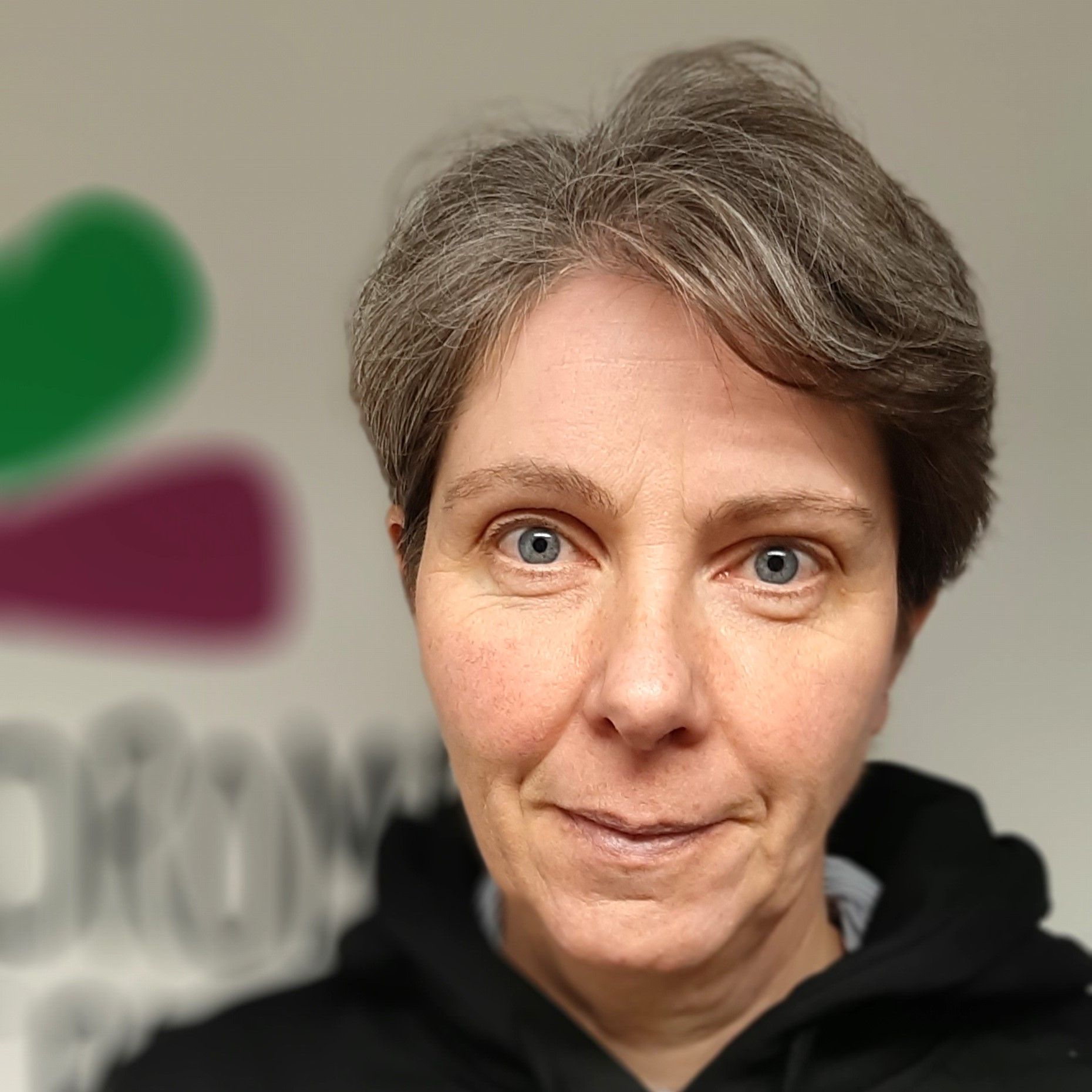 a woman wearing a black hoodie is smiling for the camera
