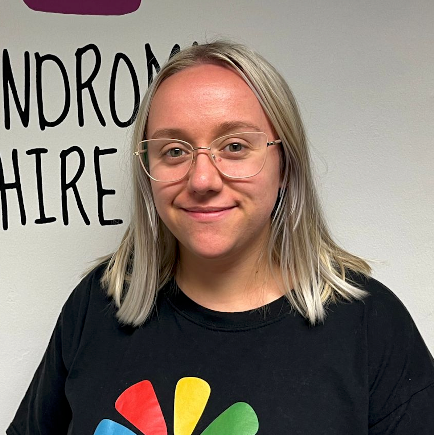 a woman wearing glasses and a black shirt is smiling .