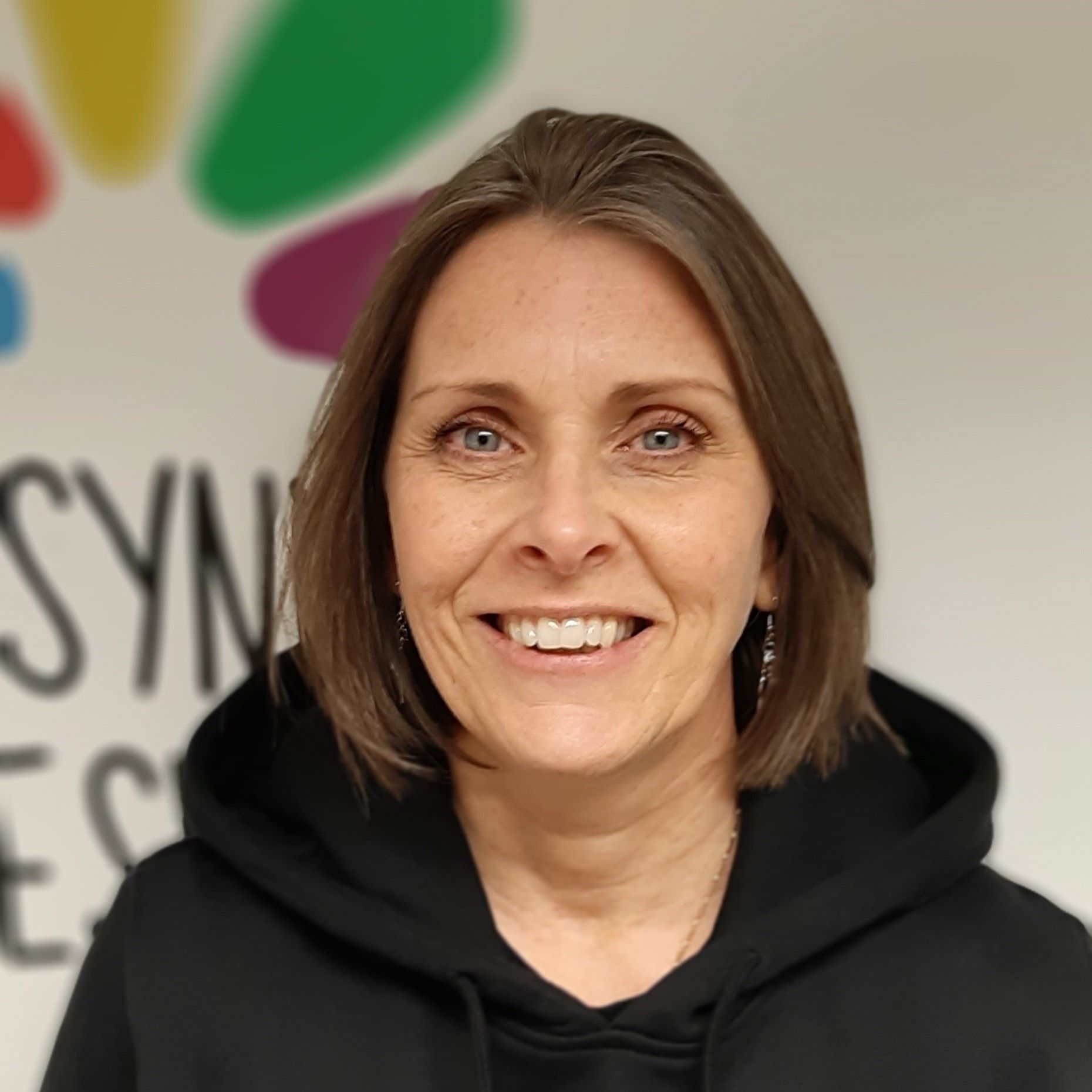 a woman in a black hoodie is smiling for the camera .