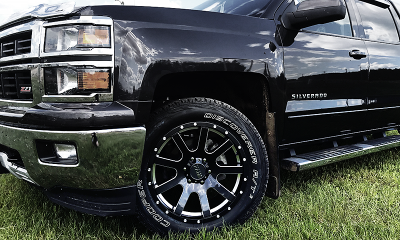 A black truck is parked in a grassy field