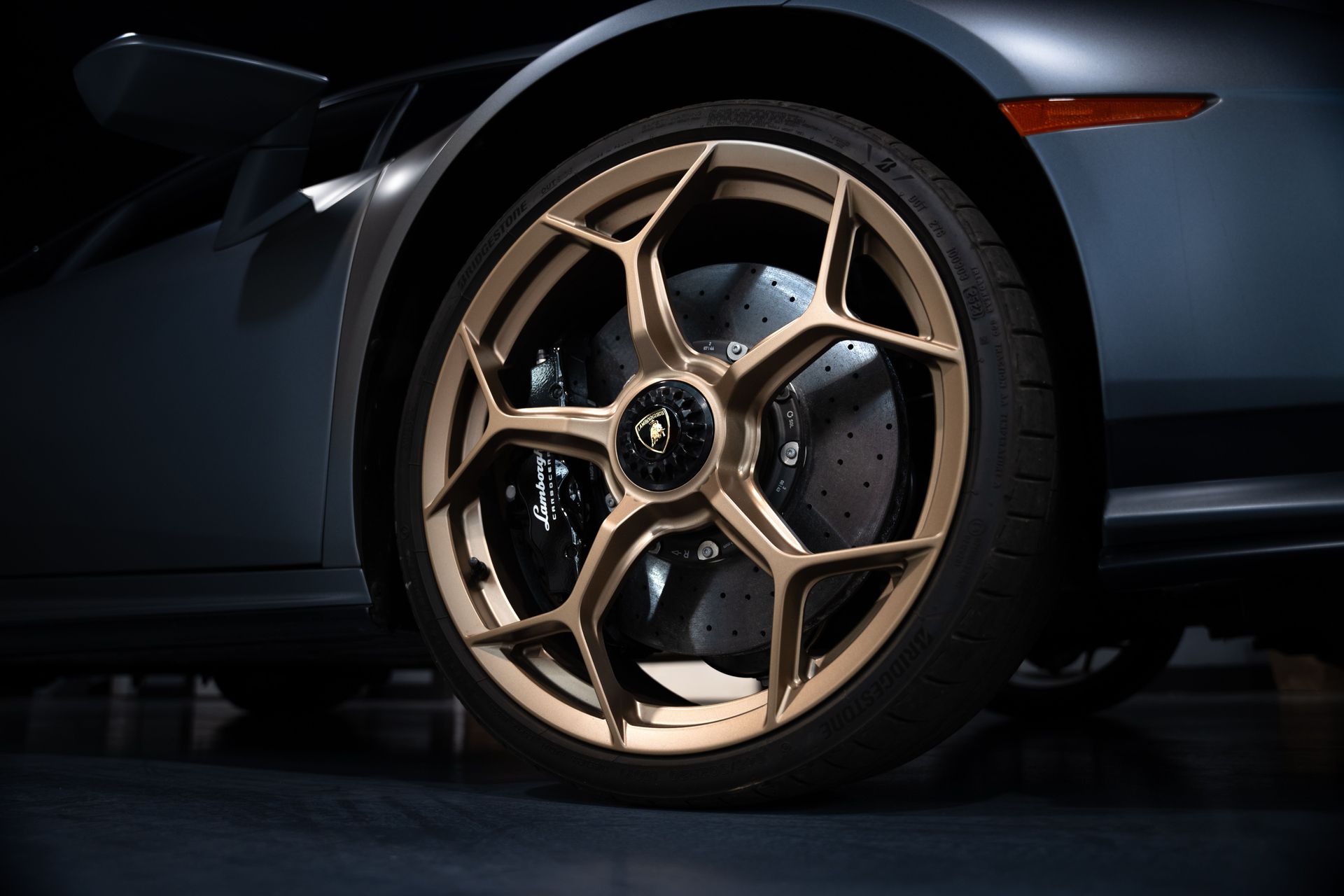 Close-up of a dark sports car’s bronze alloy wheel and tire in low light