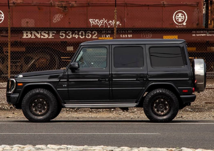 A black suv is parked in front of a bnsf train car