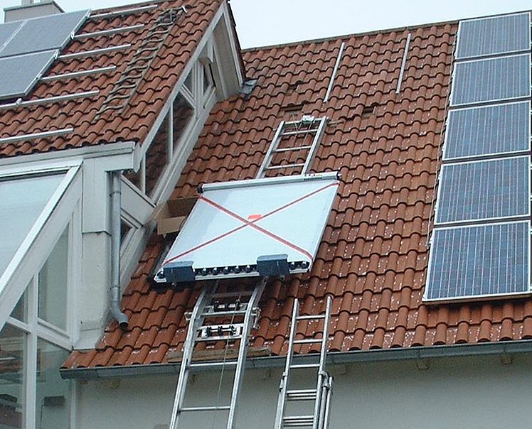 Une échelle est attachée à un panneau solaire sur le toit d'une maison