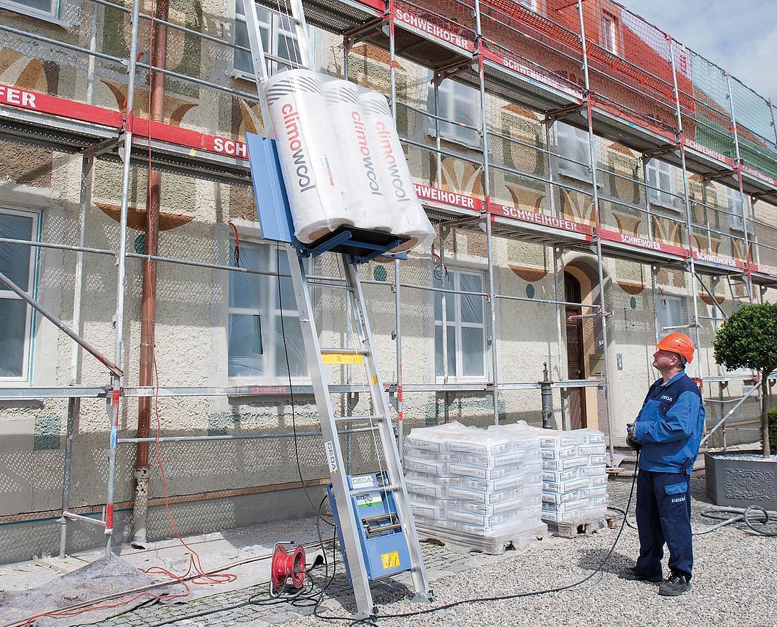 Un ouvrier du bâtiment se tient devant un bâtiment avec un échafaudage.