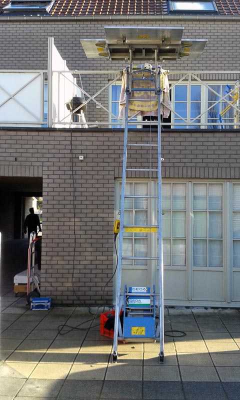 Une échelle est posée devant un bâtiment en briques.