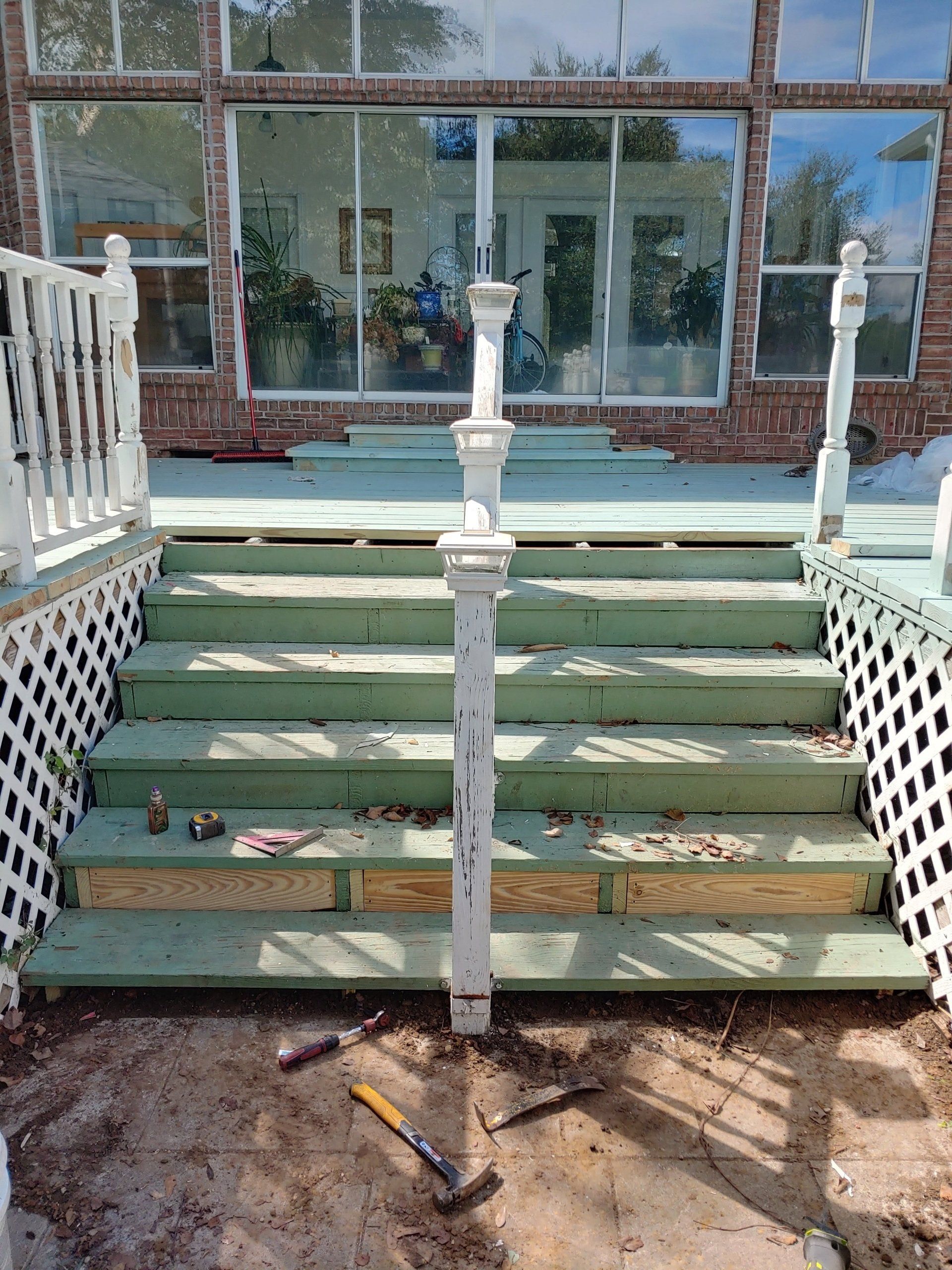 A wooden deck with stairs and a white railing is being built.