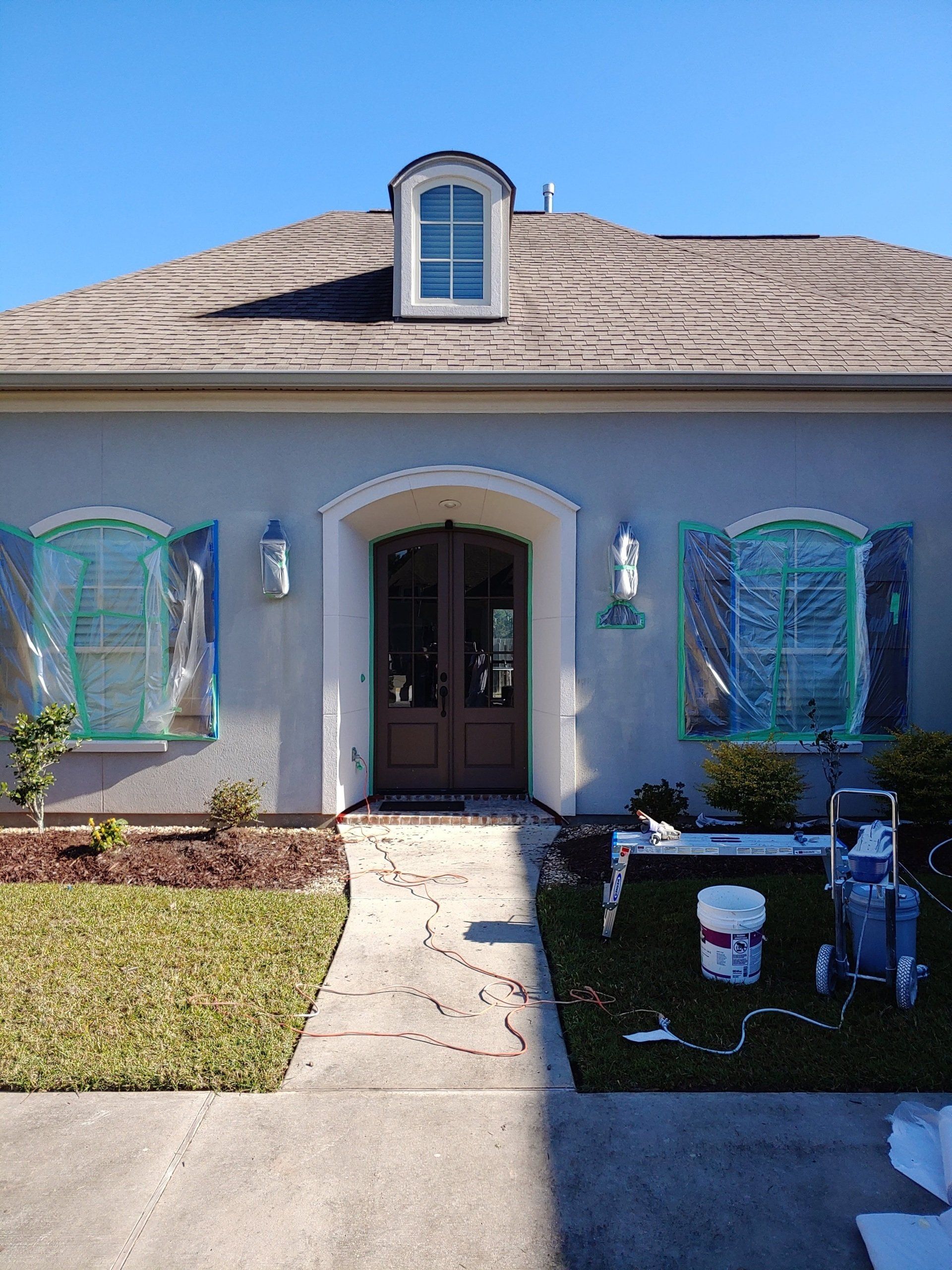 A house is being painted with a bucket of paint in front of it.