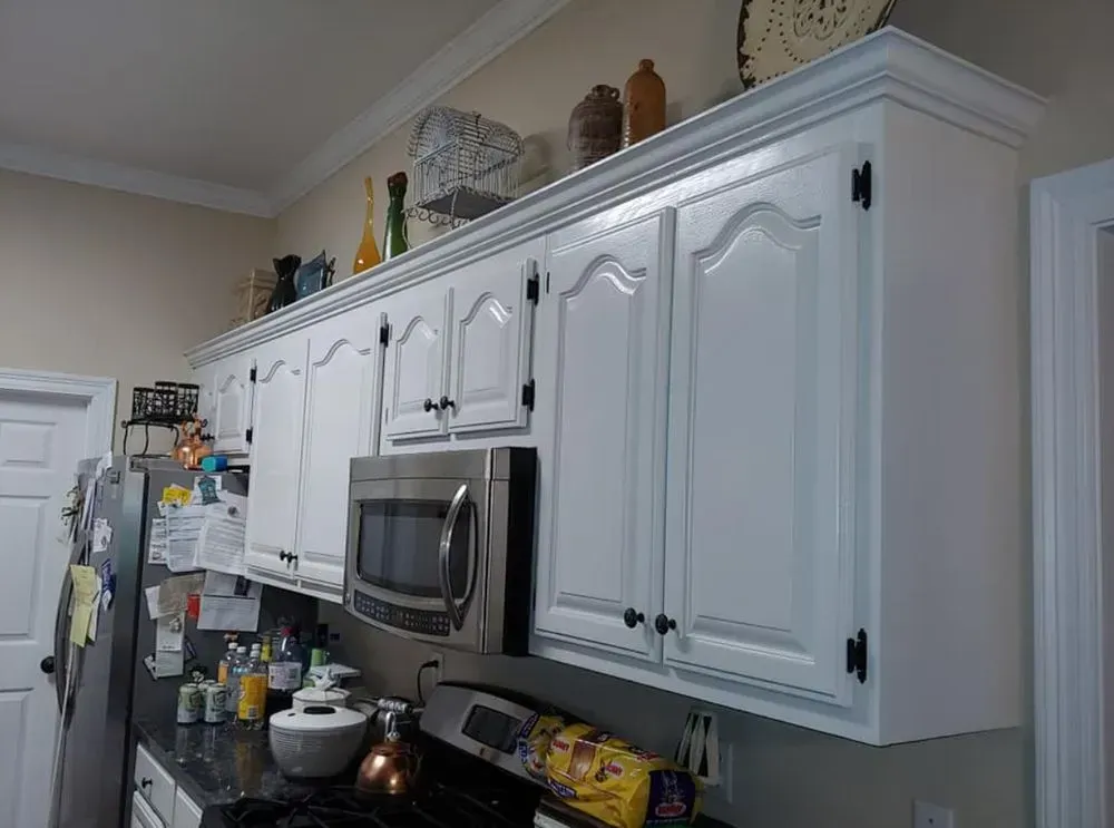A kitchen with white cabinets , a microwave , a refrigerator , and a stove.