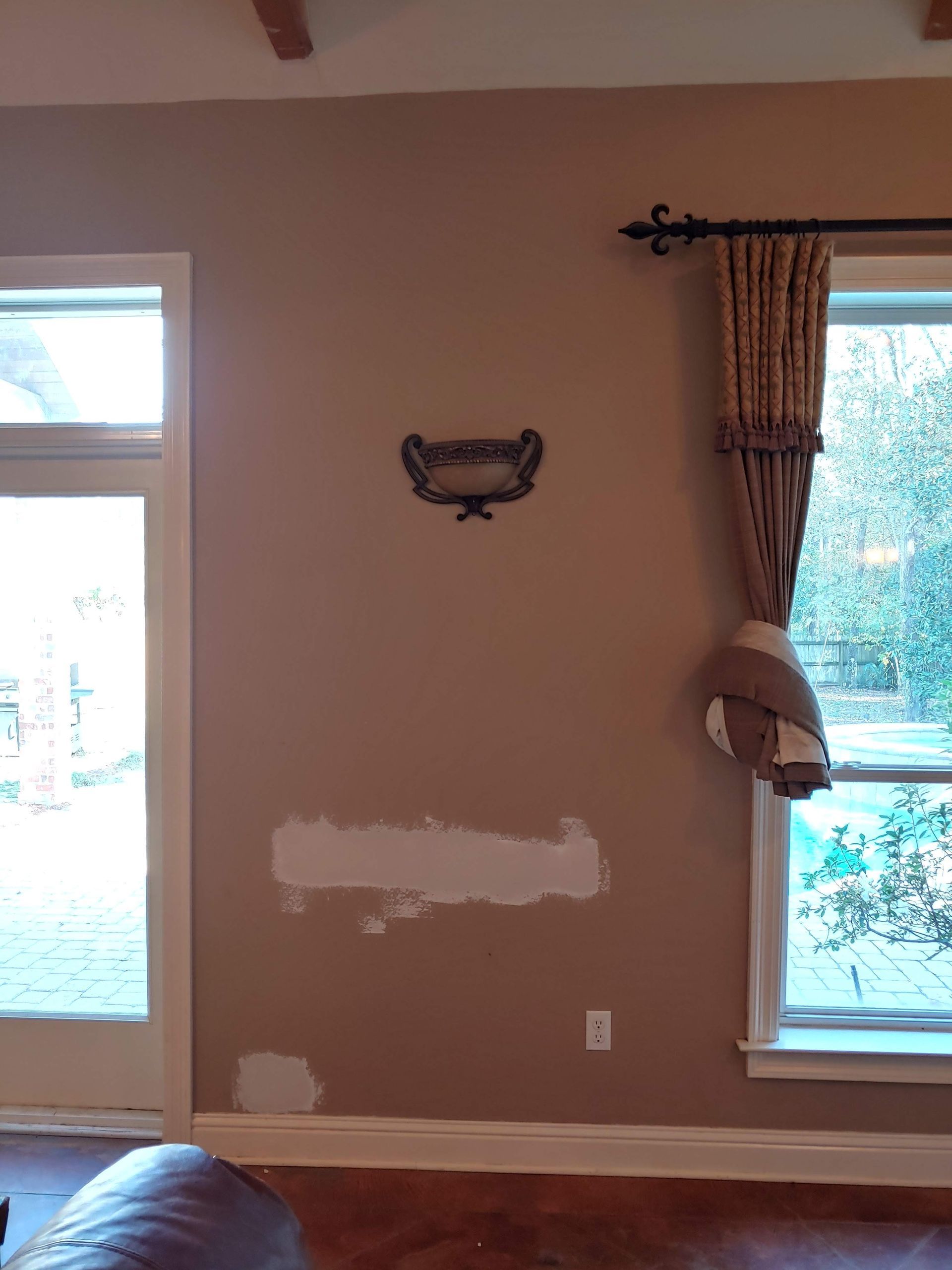A living room with a couch , a window and a shelf on the wall.