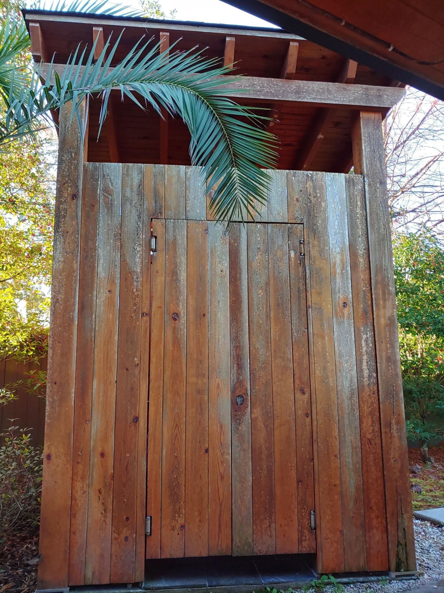 A wooden shed with a palm tree in the background
